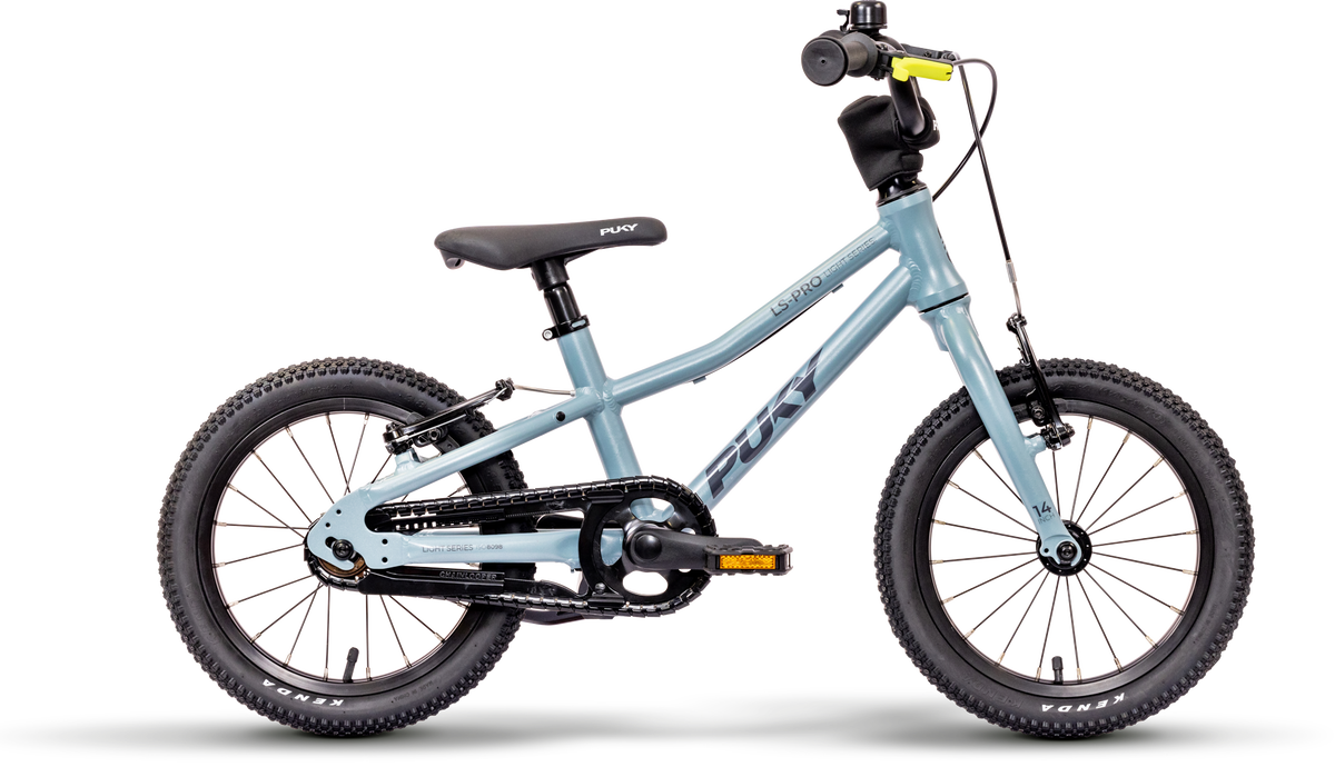En ljusblå PUKY LS-PRO 14 barncykel med en lätt aluminiumram, svarta däck, svart sadel och styre, inga stödhjul, "PUKY"-märke på ramen, handbromsar och ett kedjeskydd.