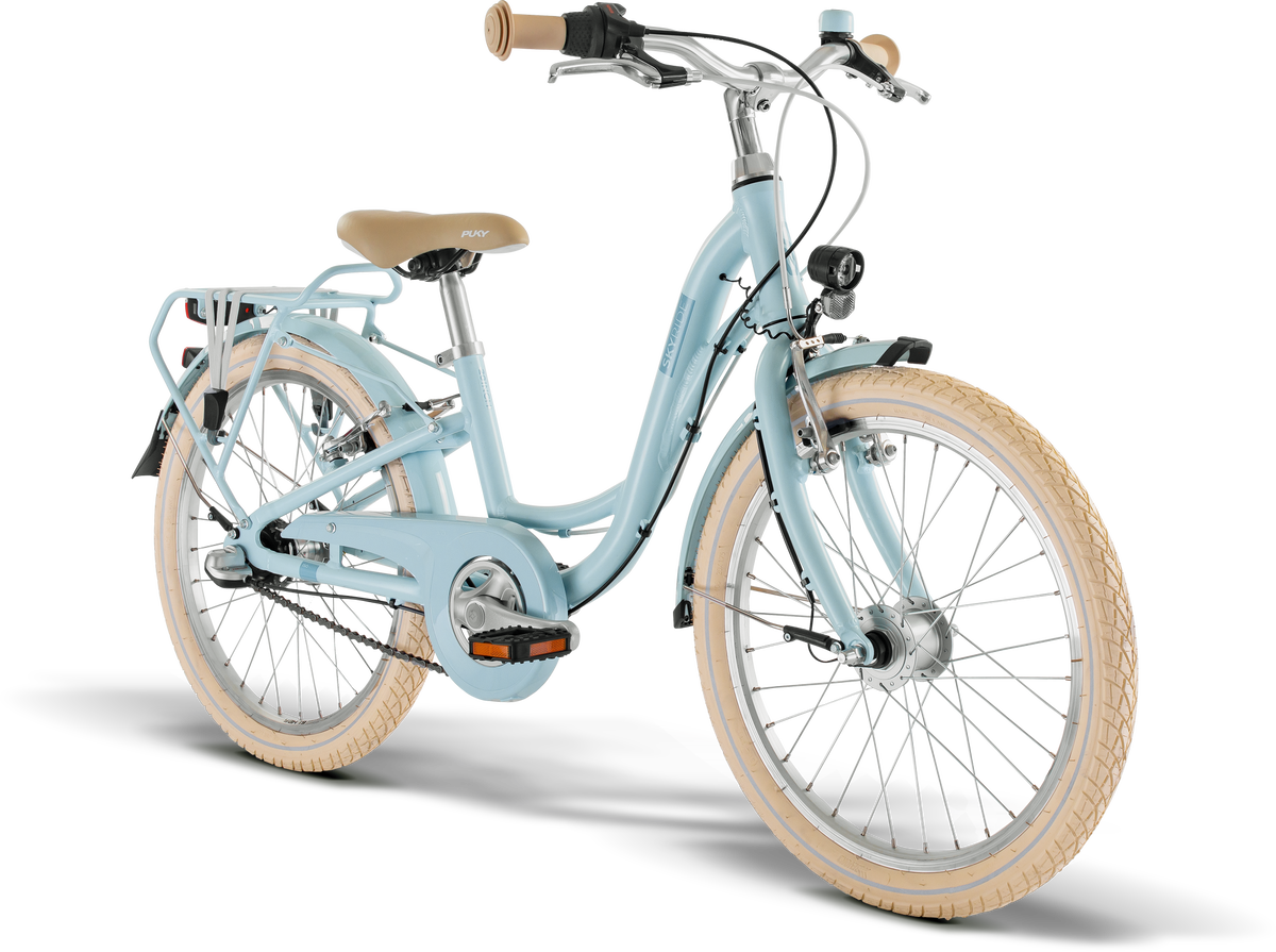 PUKY SKYRIDE 20-3 är en ljusblå genomgångscykel med beige däck, matchande sadel och handtag, stänkskärmar fram och bak, lasthållare bak och framlampa, visad framifrån mot en vit bakgrund.