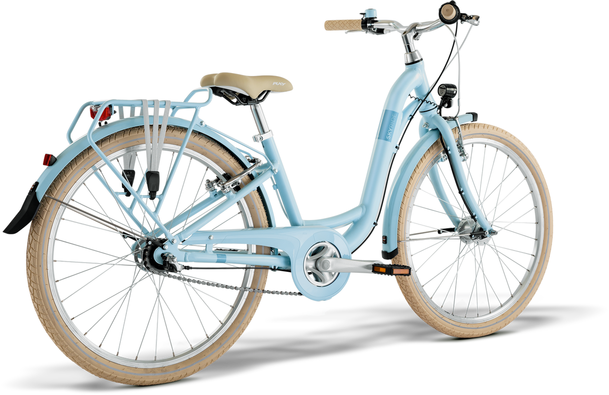 PUKY SKYRIDE 24-3 är en ljusblå citycykel med beige däck, matchande sadel, lasthållare bak och stänkskärmar fram och bak, visad bakifrån mot en vit bakgrund.