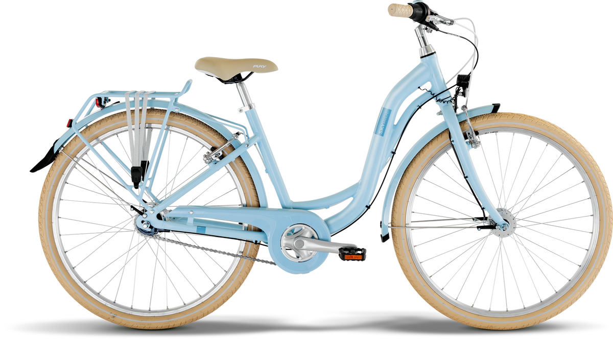 PUKY SKYRIDE 26-7 CLASSIC är en ljusblå, genomgående stadscykel med cremefärgad sadel och handtag, brunbruna däck, pakethållare bak, fram- och bakskärmar samt kedjeskydd, på vit bakgrund.