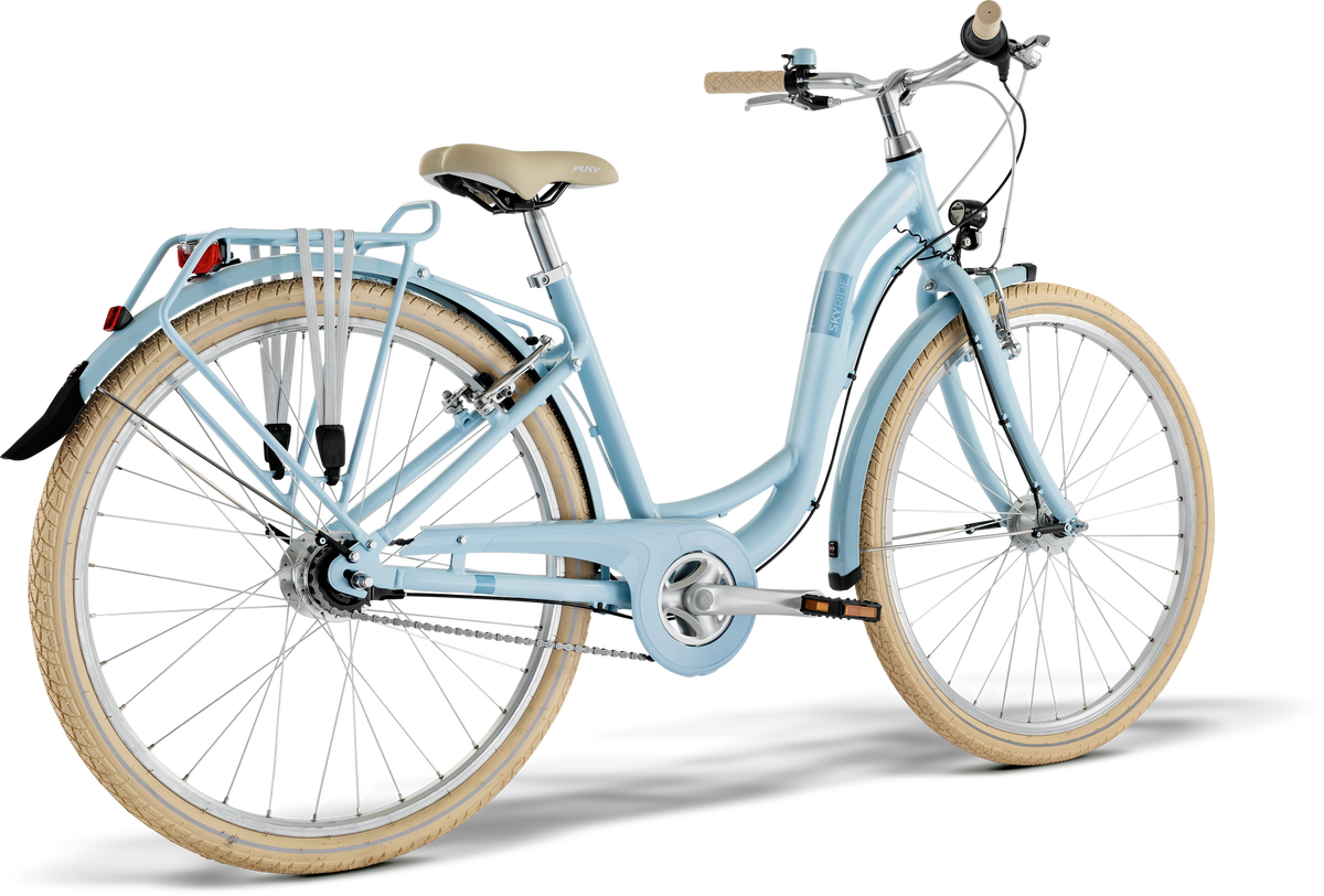 PUKY SKYRIDE 26-7 CLASSIC är en ljusblå stadscykel med beige däck, sadel och styre, med pakethållare bak och svart bakskärm. Visas på en vit bakgrund.