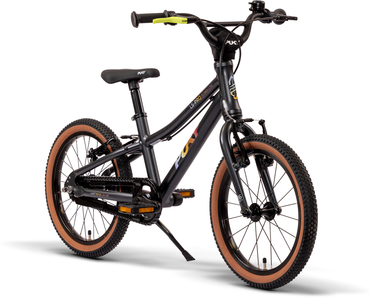 En svart PUKY LS PRO 16-2 FLOWMATIC barncykel med bruna däck, sparkstöd och rakt styre visas mot en vit bakgrund. Cykeln har handbromsar fram och bak och har PUKY-märket på ramen.