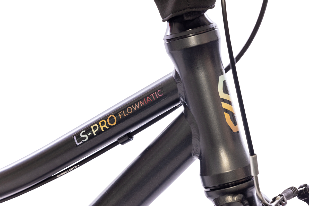 Närbild av en mattsvart PUKY LS PRO 16-2 FLOWMATIC cykelram, med överröret märkt i gult och orange, och en del av headsetet och kabeln syns också.