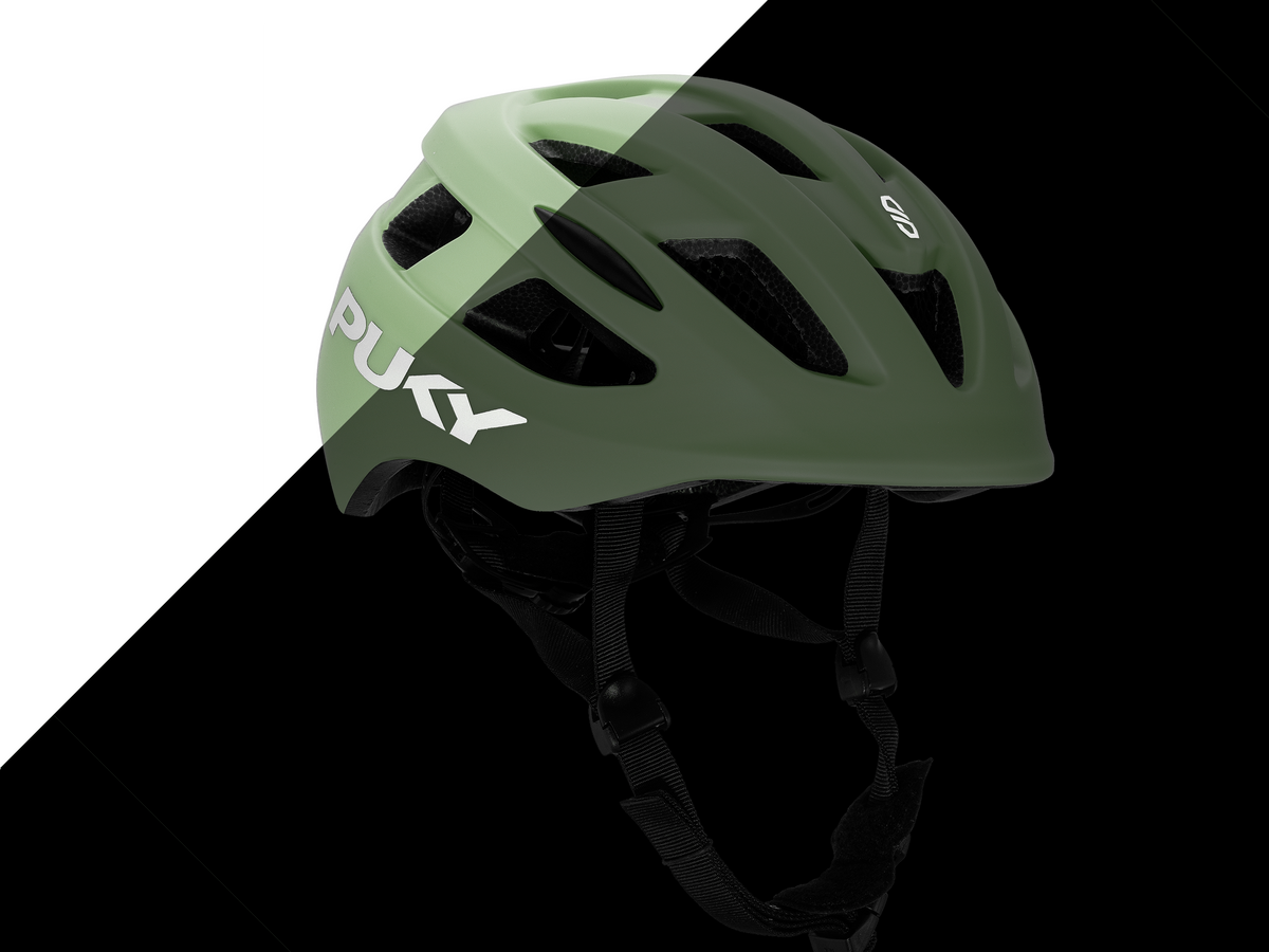 PUKY HELMET M från PUKY, med grön PU-finish och svarta remmar, visas på en diagonalt uppdelad svartvit bakgrund.